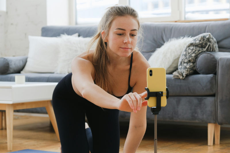 An influencer at work, recording yoga on her cellphone