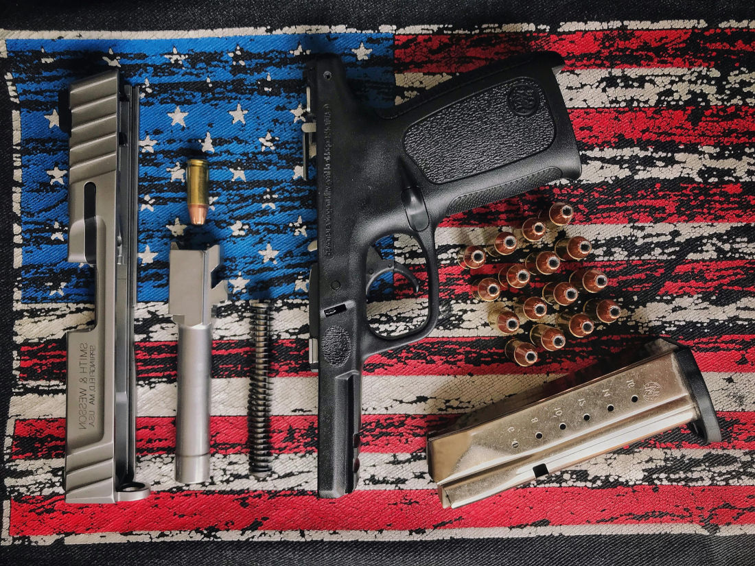 A disassembled handgun with the USA flag as background